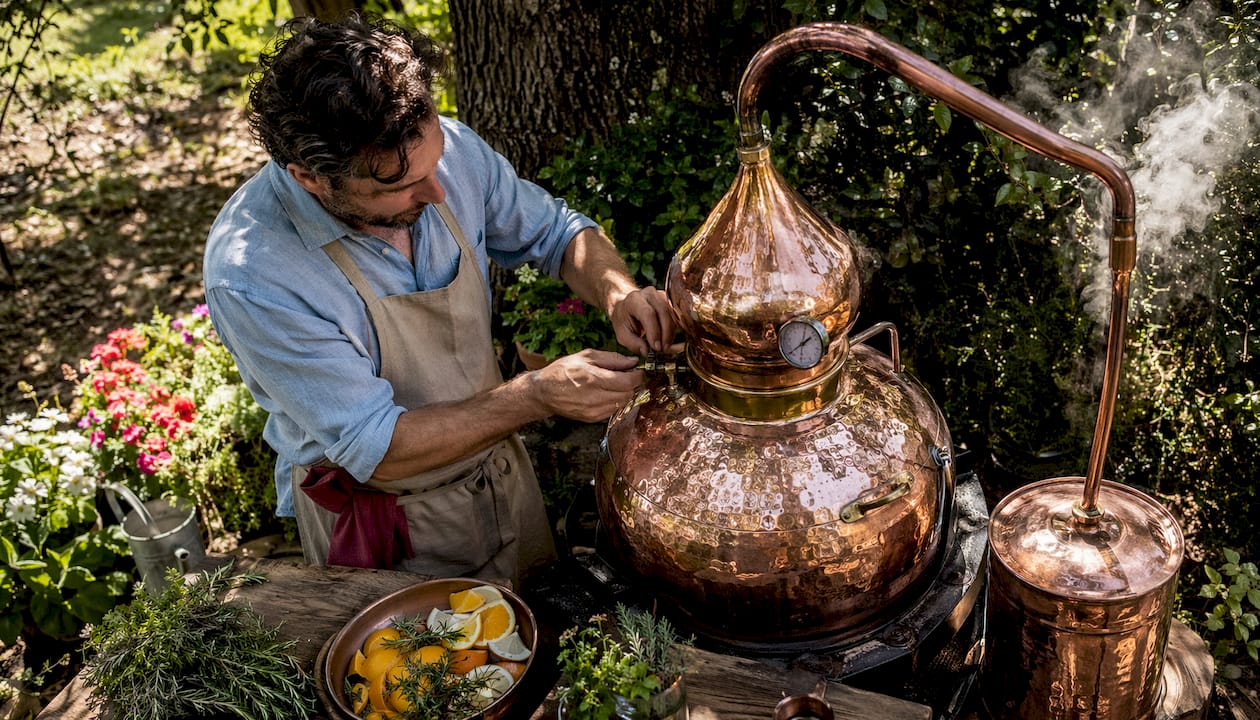 Artisan distillateur à l’œuvre, surveillant avec soin son alambic en cuivre.