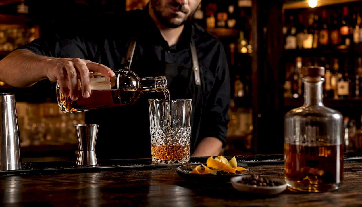 Un barman sert un rhum épicé du terroir pour préparer un cocktail raffiné.