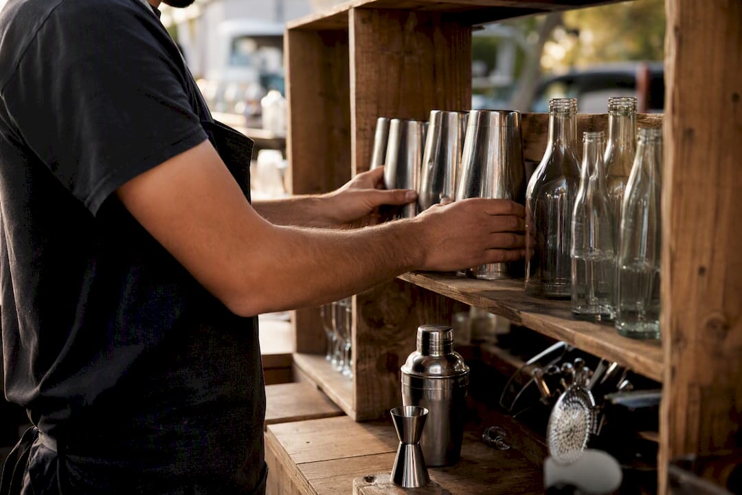 Des mains s’affairent à monter des étagères provisoires pour le bar.